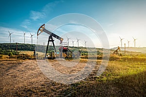 Oil pump and wind turbines against incredible sunset sky. Industrial concept