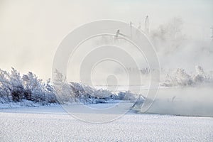 The  oil pumping unit in morning mist in winterlakeside