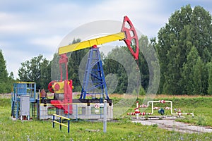 The oil pumpjack stands among the trees