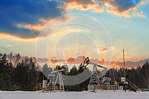 Oil pumps. Russia Oil industry equipment. Oil rig energy industrial machine for petroleum crude. Oil crisis. Fiery red clouds from