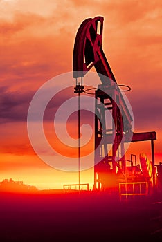 Oil pumps at sunset, industrial oil pumps equipment. Sunset and darkness. Oil field in the fog. Red toning. Crisis in