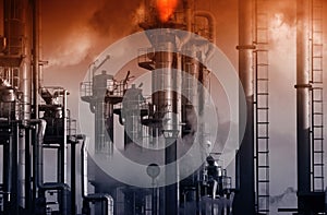 Oil refinery with burning safety flames and red sky