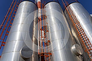 Oil Refinery Exterior with Storage Tanks Over Blue Sky Background