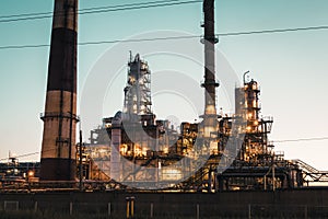 Oil refinery industrial plant or factory at sunset, storage distillery tanks and steel pipeline, modern petrochemical technologies