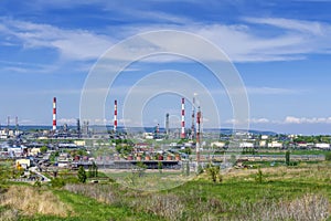 Oil refinery, pipes, burning torch, crackers, hulls, storage tanks for petroleum products, against the backdrop of green