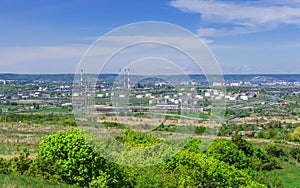 Oil refinery, pipes, burning torch, crackers, hulls, storage tanks for petroleum products, against the backdrop of green vegetatio