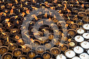 Oil religious candles glowing with orange flames on a hindu temple. Symbols of faith and religion and for wishes and