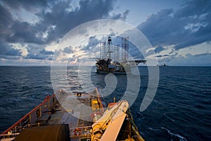 Oil rig platform towed by an offshore vessel during sunset