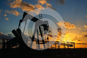 Oil rig silhouette pumping at evening