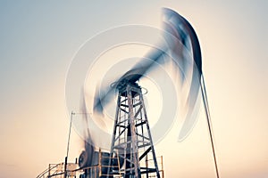 Oil rig silhouette working at sunset. Blur at slow shutter speeds