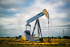 Oil Rig with Wind Turbines in the Background of West Texas Landscape