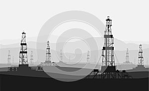 Oil rigs at large oilfield over mountain range.