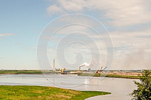 Oil sands refinery industry landscape with a lake in the front