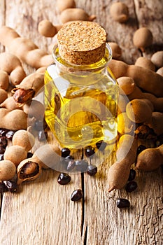 Oil from the seeds of Tamarindus indica in a glass jar close-up on a table. vertical