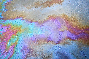 Oil stain on the asphalt, rainbow-shaped colored gasoline stains on an asphalt road