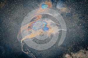 An oil stain on the asphalt, rainbow-shaped colored gasoline stains on an asphalt road