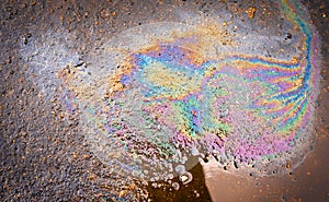 Oil stain on the asphalt, rainbow-shaped colored gasoline stains on an asphalt road as a texture or background