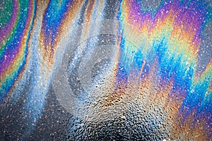 Oil stains from leaks in the car engine. Oil after rain makes spots with rainbow reflections refractive sun spectrum.
