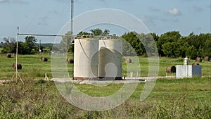 Oil storage tanks with hay bales in the background in the State of Oklahoma in the United States of America.