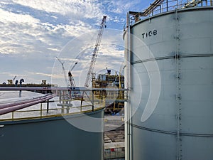 Oil storage tanks in an industrial area with the background of the oil rig construction process