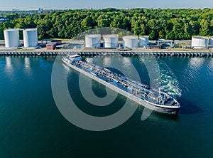 Oil tanker sailed out from an oil storage silo terminal after unloading. Aerial view of oil tankers and storage silo tanks at a pe