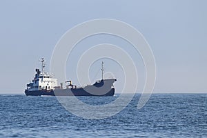 Oil tanker ship sailing in the ocean in sunny day, calm blue sea.