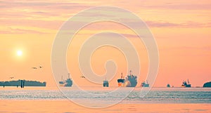 oil tanker ships and fishing boats sailing in the sea against golden sunrise sky background in the morning