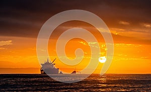 Oil tankers ship at sea on a background of sunset sky.