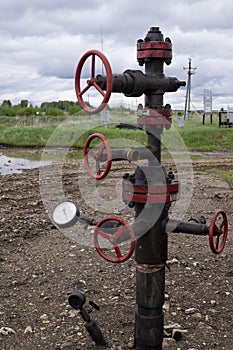 Oil valves and piping. production wellhead. A natural oil well. Horizontal view of a wellhead with valve armature. Oil and gas