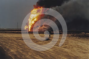 Oil well burning in field with remains of burned tank