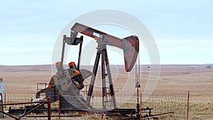 Oil Well Pump Jack pumping crude oil for fossil fuel energy. American Petroleum Oil and Gas Industry equipment extracting from a