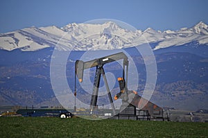 Oil Well pump jack and Snow Capped Peaks