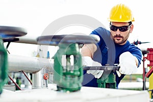 Oil worker turning valve on oil rig