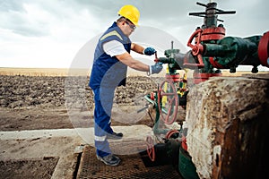 Oil worker is turning valve on the oil pipeline. Oil and Gas Industry.