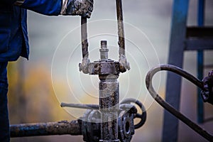 Oil workers check oil pump. Roustabouts doing dirty and dangerous work