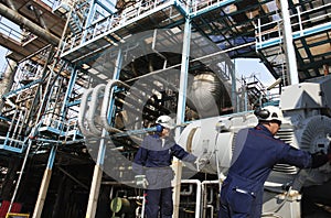 Oil workers with large refinery in background