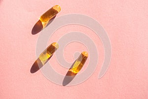 Oil yellow capsules on pink background