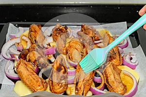 oiling raw chicken wing with onion
