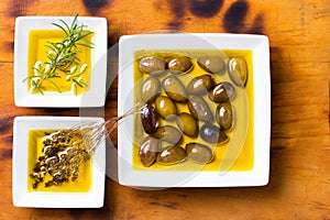 Oilive oil with olives and herbs on wooden background photo