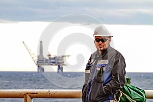 Oilman shift workers on the deck of the ship on the background offshore oil shelf planforms. Work on the way to work