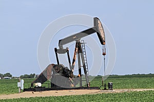 Oilwell pump with blue sky in a farm field