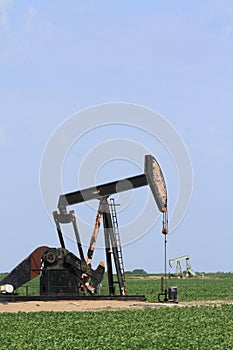 Oilwell pump with blue sky in a farm field photo