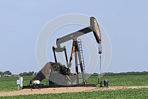 Oilwell pump with blue sky in a farm field photo