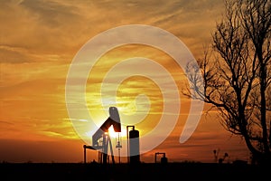 Oilwell Pump Silhouette with a colorful Sunset and tree`s in Kansas. photo