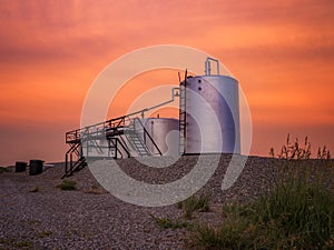 Oilwell at sunset with an orange and pink sky Landscape
