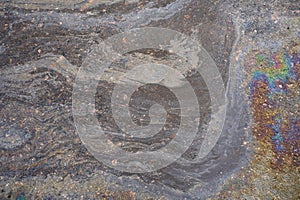 Oily film of rainbow oil or gasoline spill on the surface of a puddle, top view.