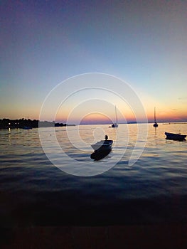 Oily sea at sunset with boats at rest on the sea of Pag in Novalja