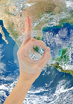 Ok hand gesture against the backdrop of the planet Earth NASA