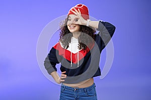 Okay girl agrees. Friendly-looking happy and charming young curly-haired girl in warm beanie showing ok gesture or
