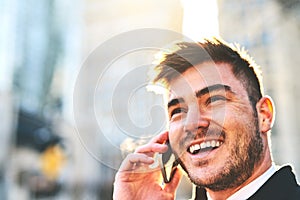 Okay great Ill meet you there. a cheerful young man talking on his phone while waiting for a taxi to take him to work in